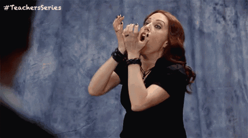 a woman with red hair is screaming in front of a wall with #teachersseries written above her