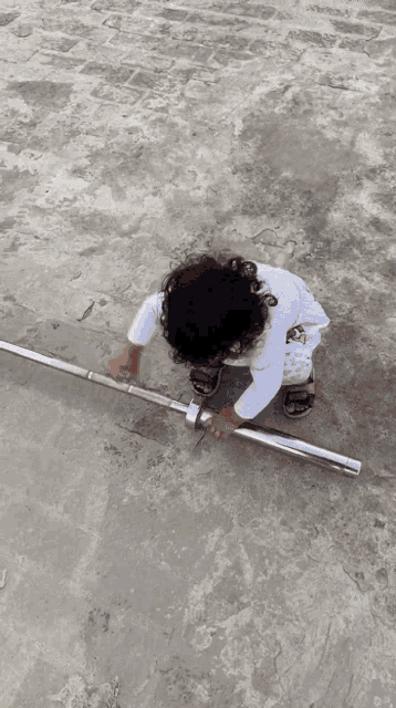 a little girl is playing with a metal barbell
