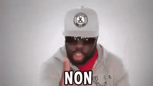 a man wearing a hat , sunglasses and a hoodie is making a funny face and saying non .