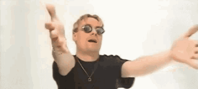 a man wearing sunglasses and a necklace is making a funny face .