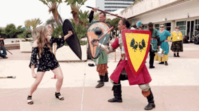 a woman stands in front of a man with a shield that says ' a ' on it