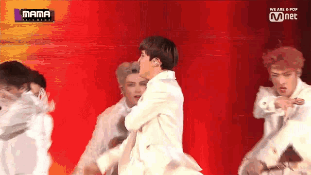 a group of young men are dancing on a stage with a sign that says mama on it