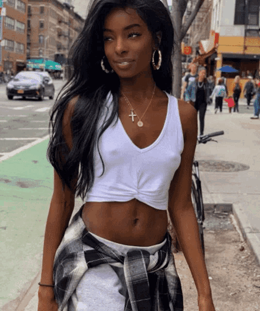 a woman wearing a white tank top with a cross on it