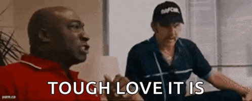 two men are sitting on a couch and one of them is wearing a hat that says tough love it is