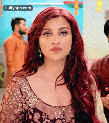 a woman with red hair is wearing a purple and gold dress and earrings .