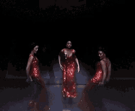 a woman in a red dress is dancing with two other women