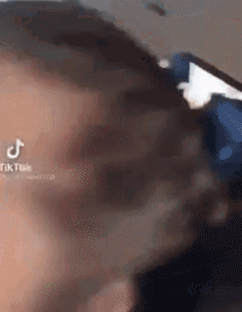 a close up of a person 's head with a blurred background and a tik tok logo .