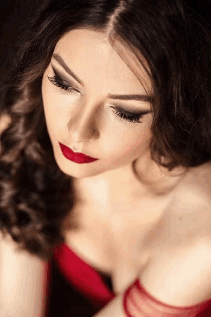 a woman in a red dress with red lipstick is looking down