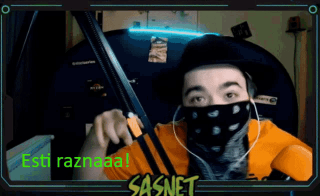 a man wearing a bandana and a hat is holding a sword in front of a sasnet screen