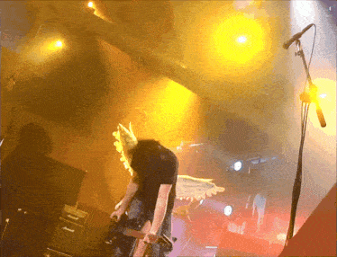 a man with wings is singing into a microphone on a stage