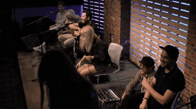 a group of people sitting in front of a microphone in a room