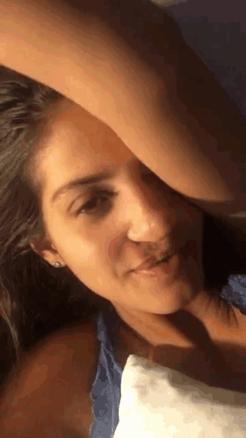 a close up of a woman 's face with her hand over her head
