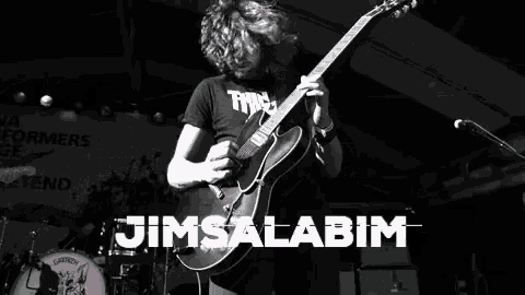 a man is playing a guitar in front of a sign that says jimsalamim
