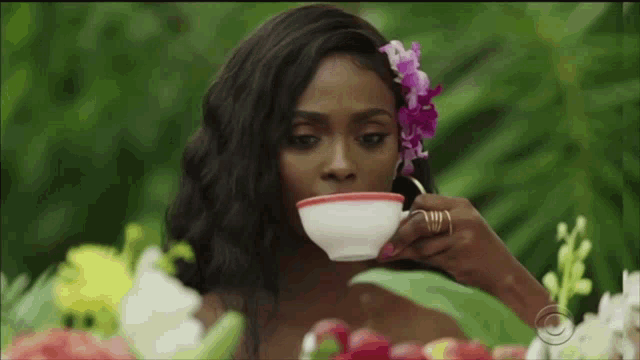 a woman with a flower in her hair drinking from a cup