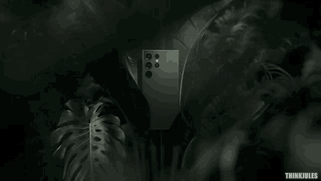 a samsung phone is surrounded by leaves and a think jules logo