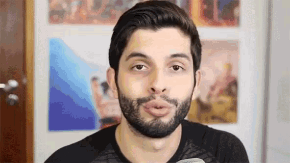 a man with a beard is making a funny face in front of a wall .