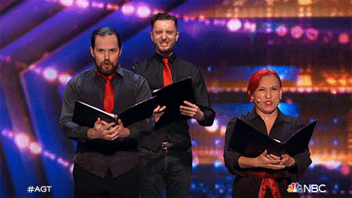 a group of people singing on a stage with a nbc logo in the background