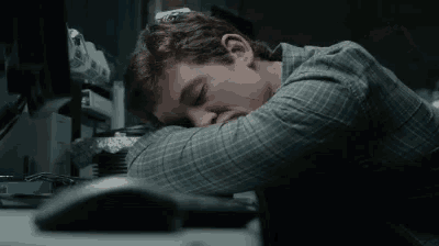 a man is sleeping on a desk in front of a computer mouse .