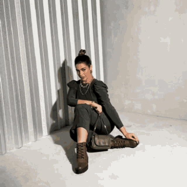 a woman is sitting on the floor with her legs crossed and holding a purse