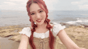 a woman with red hair is taking a picture of herself with the ocean in the background