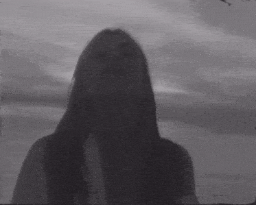 a black and white photo of a woman with long hair looking at the camera