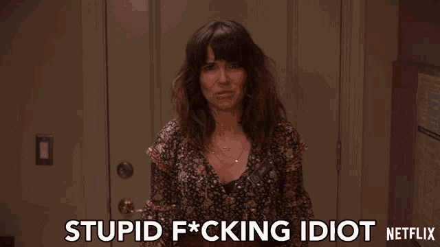 a woman is standing in front of a door with the words stupid f * cking idiot netflix on the bottom