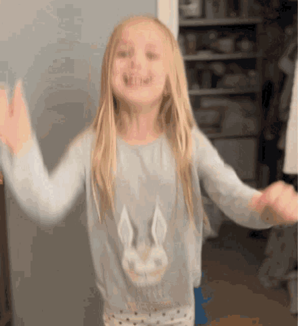 a little girl wearing a bunny sweater is dancing