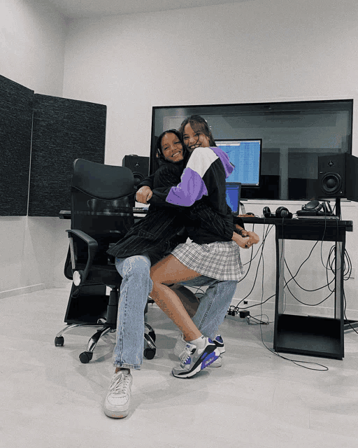a girl in a plaid skirt sits on a man 's lap in front of a computer monitor
