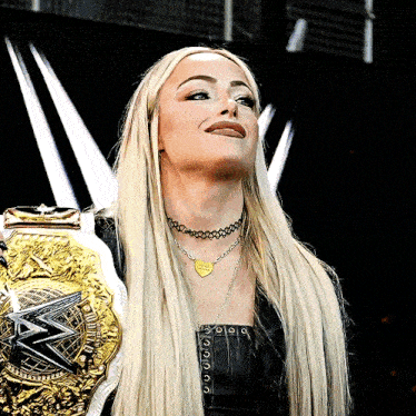 a woman wearing a necklace that says i love you is holding a wrestling belt