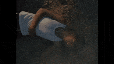 a man laying on the ground with a white tank top on
