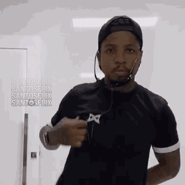 a man wearing headphones and a hat is standing in front of a white wall with the words santosflix written on it
