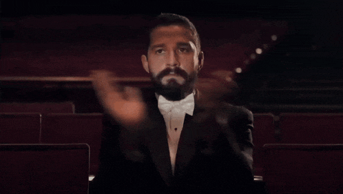 a man in a tuxedo is sitting in an auditorium