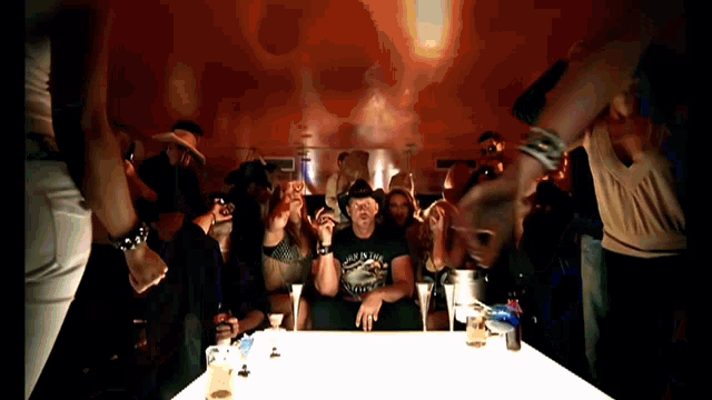 a man in a cowboy hat is sitting at a table in a crowd