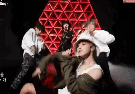 a group of people are dancing on a stage in front of a red and white triangle .