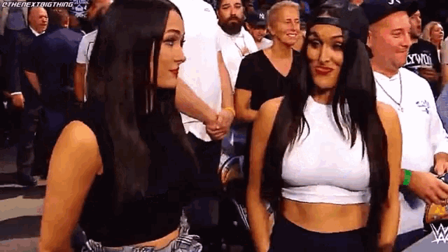 two women standing next to each other in front of a crowd .