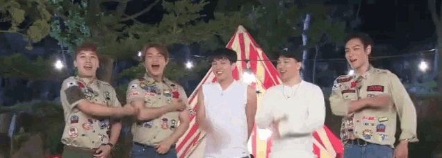 a group of young men are standing next to each other in front of a tent at night .