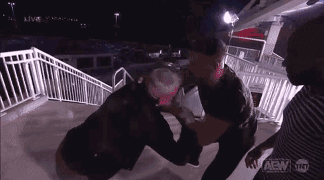 two men are fighting in front of a staircase with a sign that says aew