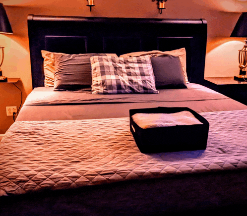 a bed with pillows and a black box on the bed