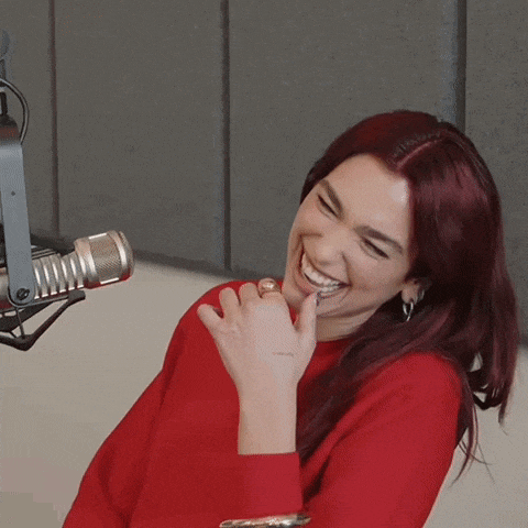 a woman in a red sweater is smiling in front of a microphone