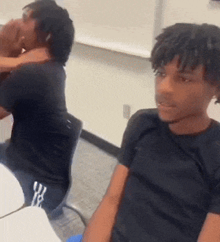 a man in a black shirt is sitting at a table with another man