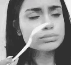a black and white photo of a woman with a spoon in her nose .