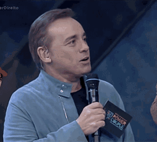 a man in a blue jacket is holding a microphone and a card that says power circle