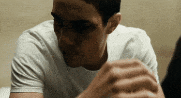 a man in a white t-shirt looks down at something