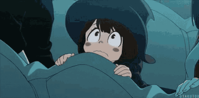 a girl in a witch hat is hiding under a blanket