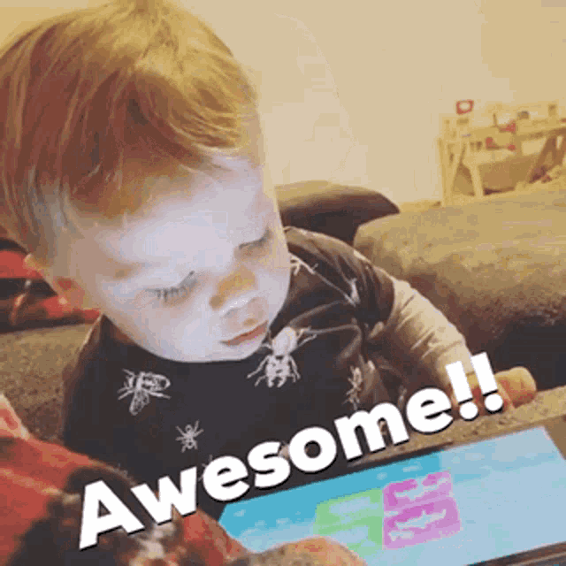a baby is sitting on a couch looking at a tablet with the words awesome written on the bottom