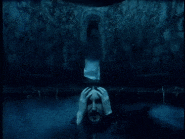 a man with his hands on his head is in a dark cave