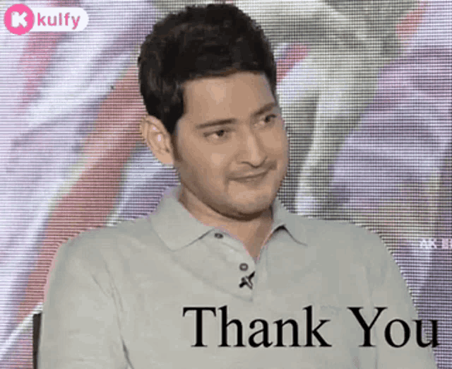 a man is sitting in front of a screen with the words `` thank you '' on it .
