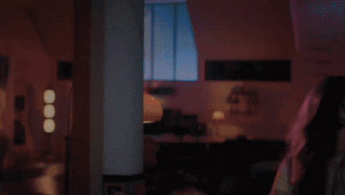 a woman with blonde hair is standing in a room with pink lights