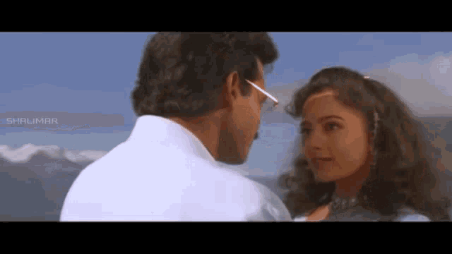 a man and a woman are looking at each other in front of mountains .