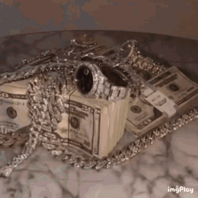 a stack of money and a watch on a table with a watermark that says imgplay